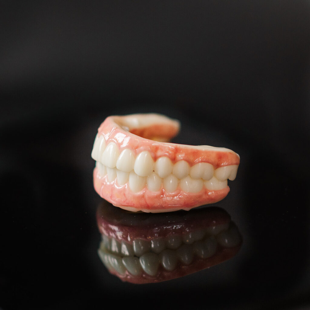Model of full-mouth dental implants against a black background
