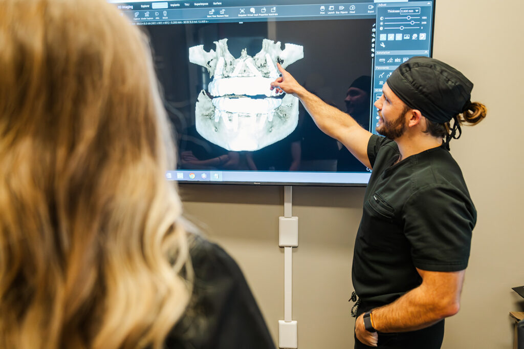 Dentist showing a 3D model of dental implants on a TV screen